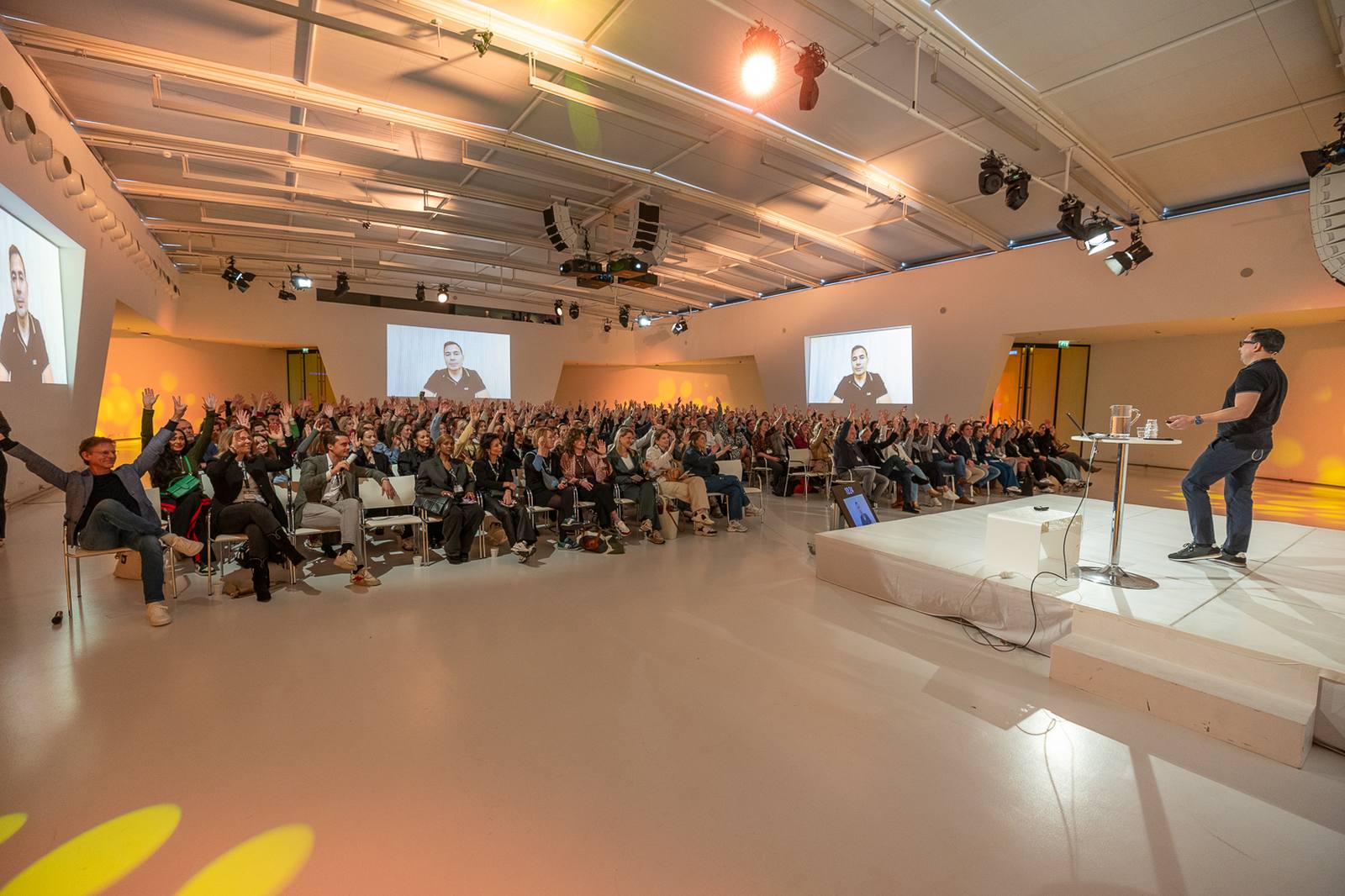 Audience with hands raised during a keynote